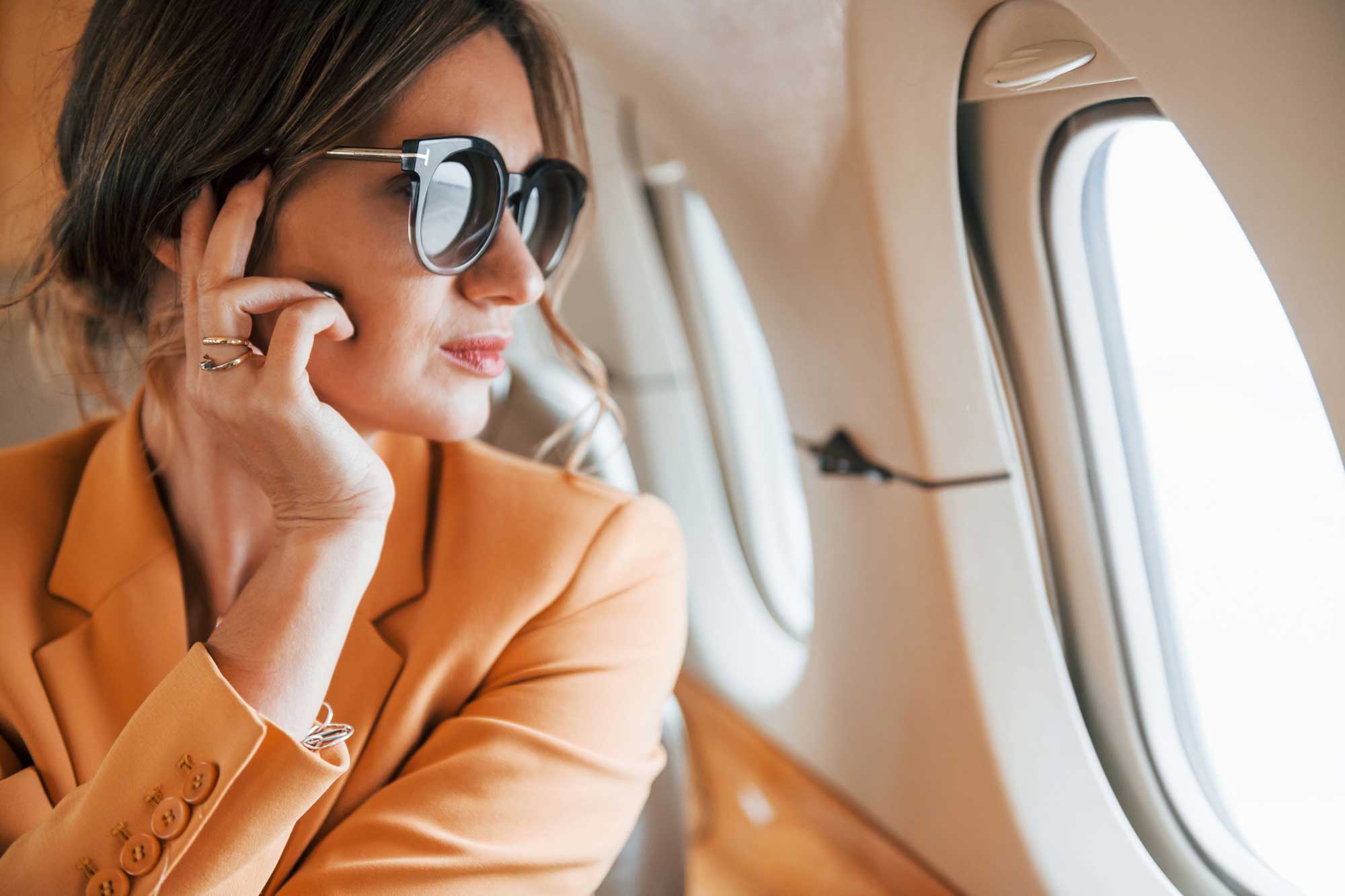 in-sunglasses.-young-passenger-woman-in-yellow-clothes-is-flying-in-the-plane
